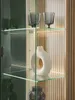 A close-up view of a glass display cabinet with decorative items on shelves. Produktbild-Vorschau