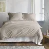 A neatly made bed with beige bedding in a room with white walls and wooden floors. Produktbild-Vorschau