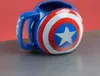 A Captain America shield-shaped mug is displayed on a metallic surface against a red background. Produktbild-Vorschau