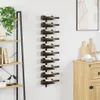A black metal wine rack mounted on a white wall, holding ten bottles of wine. To the left is a bookshelf with books and a plant. To the right is a wooden cabinet with cutting boards and glasses. Náhľad obrázku produktu
