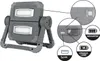 A close-up view of a gray LED work light with callouts showing USB ports and battery indicators. Produktbild-Vorschau