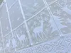 A close-up view of a white lace curtain with a Christmas theme, featuring deer and snowflakes. Produktbild-Vorschau