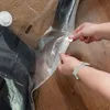 A close-up shot of hands sealing a vacuum storage bag filled with dark clothing. Náhľad obrázku produktu