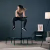 A woman is jumping on a fitness trampoline in a living room. Voir les images du produit