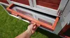 A hand is pulling out a tray from a chicken coop. Produktbild-Vorschau