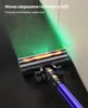 A close-up shot of a cordless vacuum cleaner head with green LED lights illuminating dust particles on a dark floor next to a white wall. Podgląd zdjęcia produktu