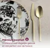 A close-up of a plate with a black and white floral design, set with a fork, knife, and spoon. Anteprima dell’immagine prodotto