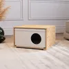 A close-up, eye-level shot of a wooden cat house with a circular opening on a light-colored rug. Produktbild-Vorschau