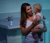 A mother holding her baby in a nursery setting. Voir les images du produit
