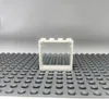A white LEGO window frame with a transparent pane, placed on a gray LEGO baseplate. Produktbild-Vorschau