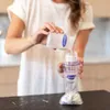 A person is pouring breast milk from a bottle into a storage bag. Podgląd zdjęcia produktu