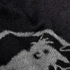 A close-up shot of a knitted fabric with a mountain and animal pattern. Produktbild-Vorschau
