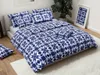 A neatly made bed with blue and white patterned bedding, pillows, and a decorative framed picture of the same pattern on a nightstand. Produktbild-Vorschau