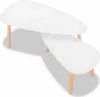 A white, tear-drop shaped coffee table set with three wooden legs each. Produktbild-Vorschau