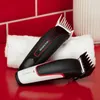 Two Remington hair clippers are placed on a white towel on a red surface, with a red tiled wall in the background. Podgląd zdjęcia produktu