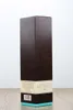 A dark brown box with a tree silhouette pattern, standing on a wooden surface against a white background. Produktbild-Vorschau