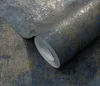 A roll of textured wallpaper with a distressed blue and gold pattern. Produktbild-Vorschau