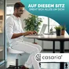 A man sits on a white rolling stool and works on a laptop at a desk. Produktbild-Vorschau