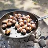 Chestnuts being roasted in a pan over coals. Produktbild-Vorschau
