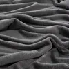 A close-up, textured view of a dark gray, soft blanket with folds and wrinkles. Produktbild-Vorschau