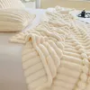 A close-up view of a soft, textured beige blanket and pillow on a bed. Produktbild-Vorschau