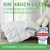 A white duvet is laid out on a bed with pillows, in a room with natural light coming from a window. Produktbild-Vorschau