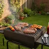 A barbecue grill with steaks, sausages, and skewers cooking in a backyard setting. Podgląd zdjęcia produktu