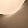 A close-up abstract shot of a ceiling light with a textured surface and a soft glow, casting subtle shadows on a textured wall. Anteprima dell’immagine prodotto