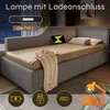 A grey upholstered sofa bed with a beige mattress and a throw blanket. There are icons and text overlays highlighting features. Produktbild-Vorschau