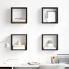 Four black cube-shaped wall shelves mounted on a white wall above a desk. Produktbild-Vorschau