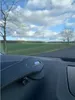 A car's dashboard with a phone holder mounted on it, with a view of a rural landscape through the windshield. Anteprima dell’immagine prodotto