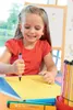 A young girl is drawing on a yellow piece of paper with a pink marker. Anteprima dell’immagine prodotto