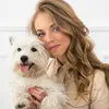 A woman is holding a white dog. Náhled obrázku produktu