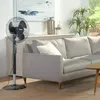 A living room scene with a fan in the foreground and a sofa in the background. Produktbild-Vorschau
