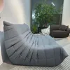 A large, gray beanbag-style sofa is positioned in a modern living room setting, with a large window and plants in the background. Anteprima dell’immagine prodotto