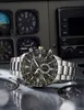 A watch is placed on a metallic surface with aviation instruments in the background. Anteprima dell’immagine prodotto