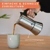 A hand is pouring coffee from a moka pot into a mug. Produktbild-Vorschau