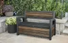 A storage bench is placed on a patio next to potted plants and stone steps, with lush greenery in the background. Produktbild-Vorschau