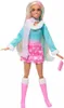 A Barbie doll standing against a white background, wearing a winter-themed outfit. Voir les images du produit