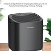 A black dehumidifier is shown on a wooden surface with green leaves in the background. Produktbild-Vorschau