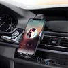 A smartphone is mounted on a car's air vent using a phone holder, displaying a music player interface. The car's dashboard and interior are visible. Anteprima dell’immagine prodotto