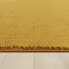 A close-up view of a yellow rug with a textured surface, resting on a light-colored wooden floor. Produktbild-Vorschau