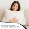 A woman is holding a white pillow on a couch. Produktbild-Vorschau