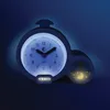 A blue alarm clock with a night light feature is shown in a dark blue environment. Produktbild-Vorschau
