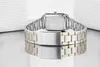 The back of a silver and gold Casio watch with a metal band is shown, resting on a reflective surface. Podgląd zdjęcia produktu