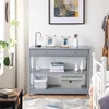 A grey console table with decorative items and books, placed in a room next to a window and a bed. Podgląd zdjęcia produktu