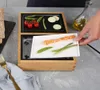 A person is placing a plate of cooked shrimp and vegetables onto a table grill. Produktbild-Vorschau