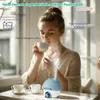 A young woman drinks from a cup while a humidifier is in use. Produktbild-Vorschau