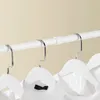 A close-up shot of white wooden hangers with white shirts hanging on a white adjustable clothes rack. Náhľad obrázku produktu