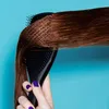 A hand with purple nail polish is holding a black hairbrush and brushing brown hair against a blue background. Anteprima dell’immagine prodotto
